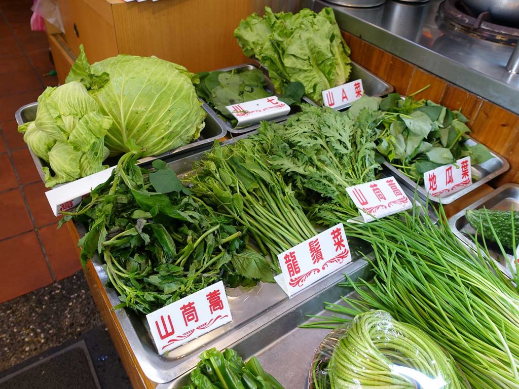 台北・烏來老街グルメ店の軒先に並ぶ山菜