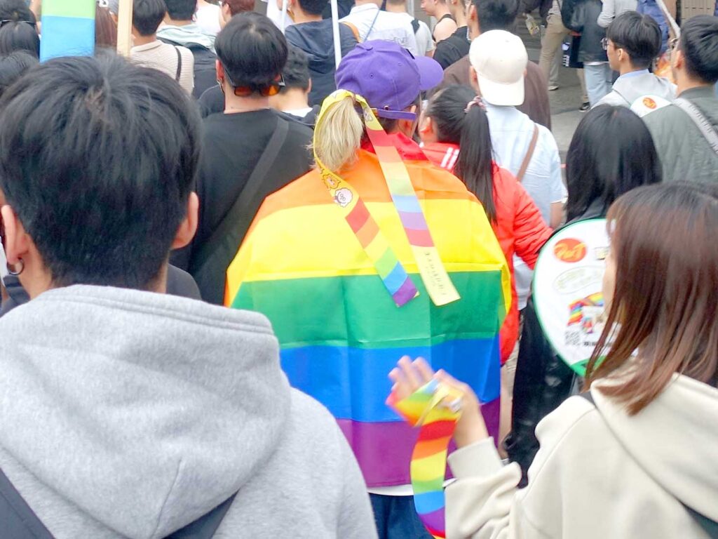 台南彩虹遊行（台南プライドパレード）2024のパレードをレインボーフラッグを纏って歩く参加者