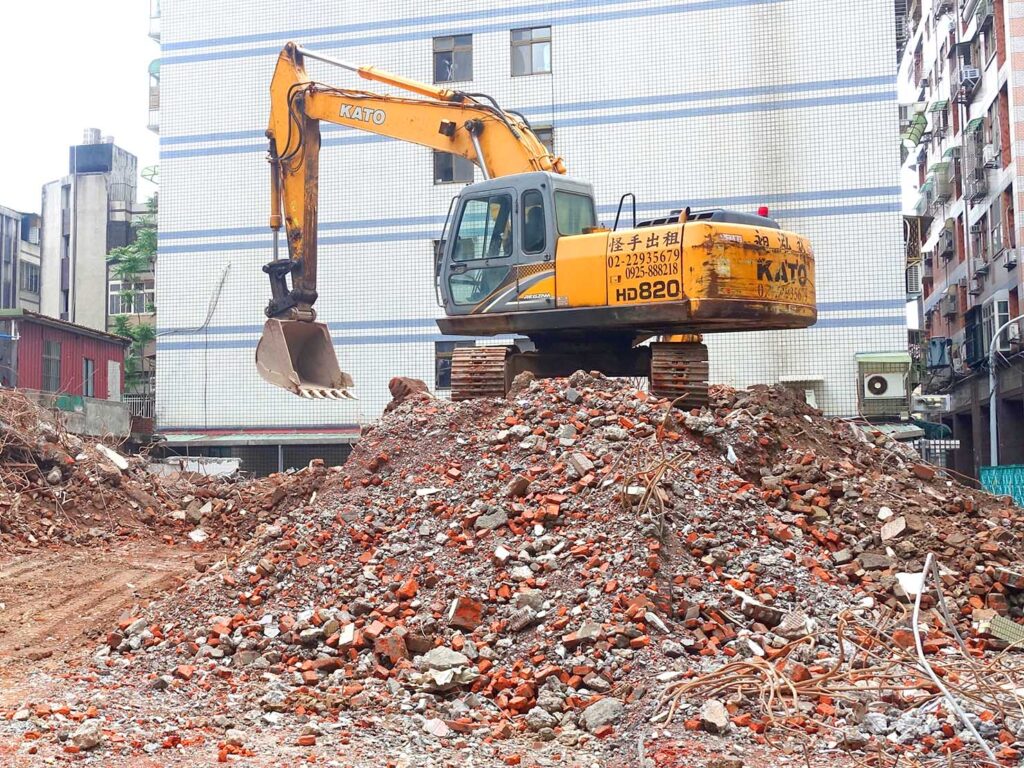 台湾の工事現場で建物を取り壊すショベルカー